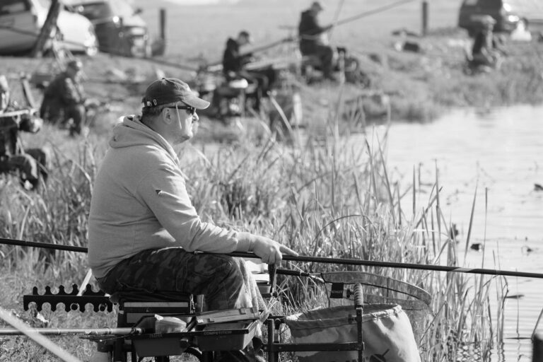Man fishing by the lakeside, enjoying a peaceful day outdoors.